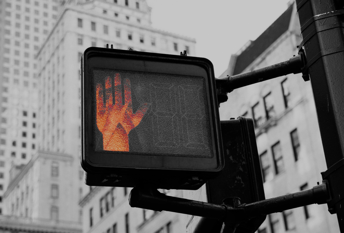 Image of a crossing walk sign showing highlighted red hand in black and white setting